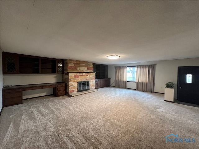 unfurnished living room featuring a stone fireplace and light colored carpet