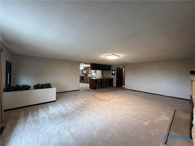 unfurnished living room featuring light colored carpet and a textured ceiling