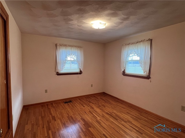 spare room with hardwood / wood-style floors and a healthy amount of sunlight