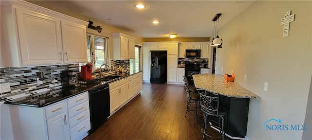 kitchen featuring hanging light fixtures, dark stone counters, sink, black appliances, and white cabinetry