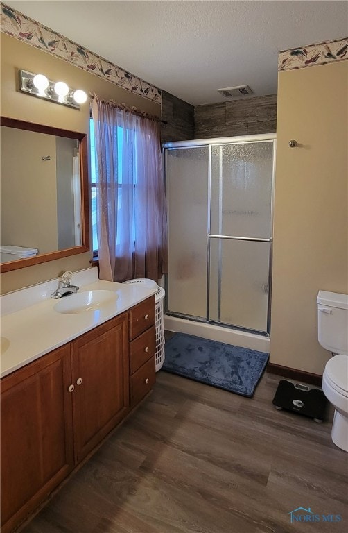 bathroom featuring a shower with door, vanity, wood-type flooring, and toilet