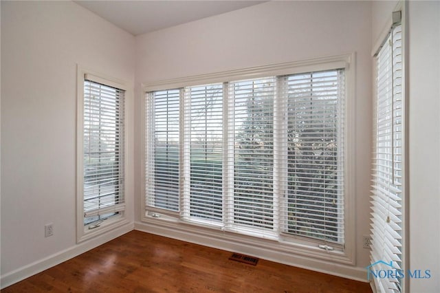 spare room with baseboards, visible vents, and wood finished floors