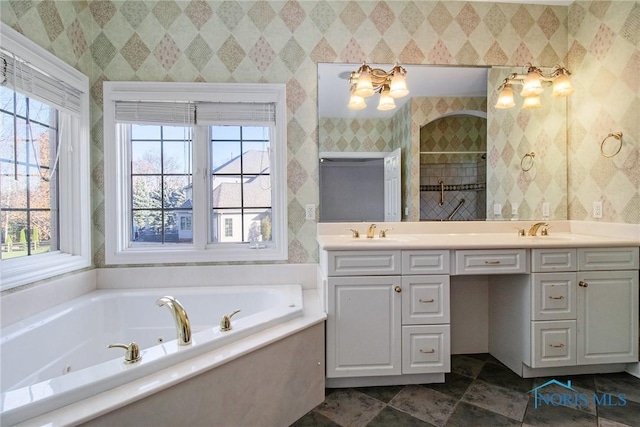 bathroom with double vanity, wallpapered walls, a tub with jets, and a sink