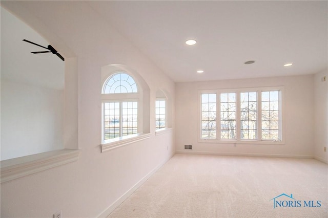 unfurnished room featuring plenty of natural light, carpet flooring, visible vents, and baseboards