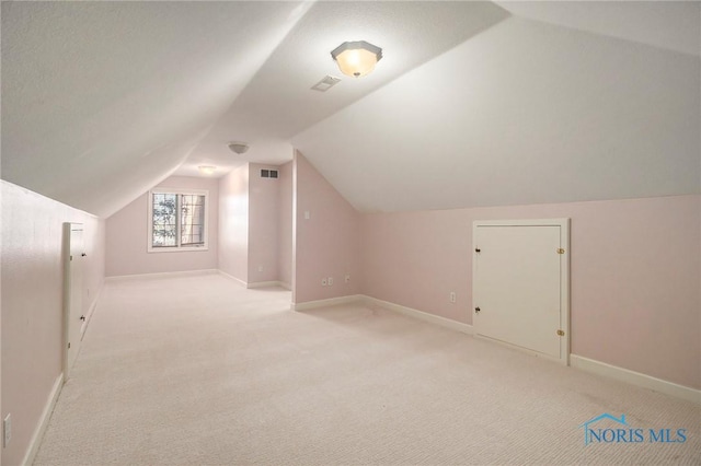 additional living space featuring lofted ceiling, baseboards, light carpet, and visible vents