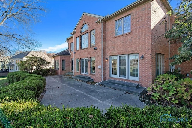 rear view of house featuring entry steps and brick siding