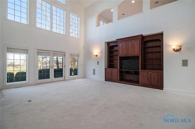 unfurnished living room with carpet floors, french doors, and baseboards