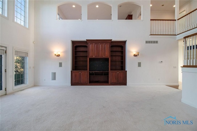 unfurnished living room featuring carpet floors, a wealth of natural light, and visible vents