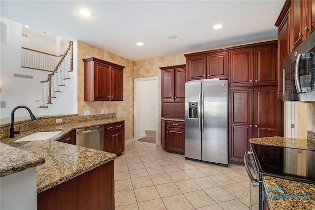 kitchen featuring reddish brown cabinets, light stone counters, stainless steel appliances, visible vents, and a sink