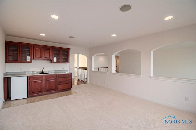 kitchen with light countertops, light colored carpet, a sink, and refrigerator