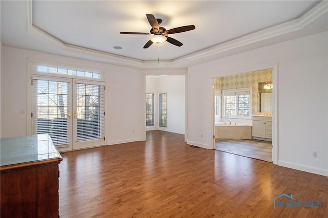 interior space featuring a tray ceiling, baseboards, and wood finished floors