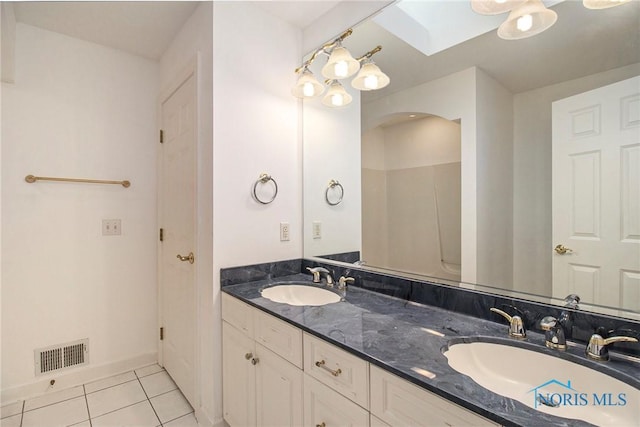 bathroom featuring a skylight, visible vents, a sink, and tile patterned floors