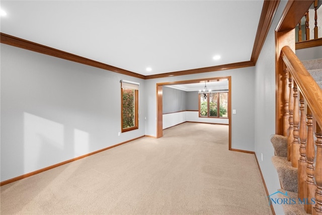 carpeted spare room with ornamental molding and a chandelier