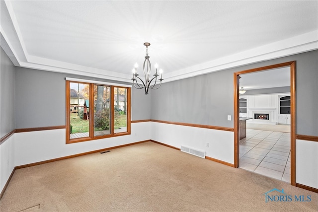 carpeted spare room with a chandelier