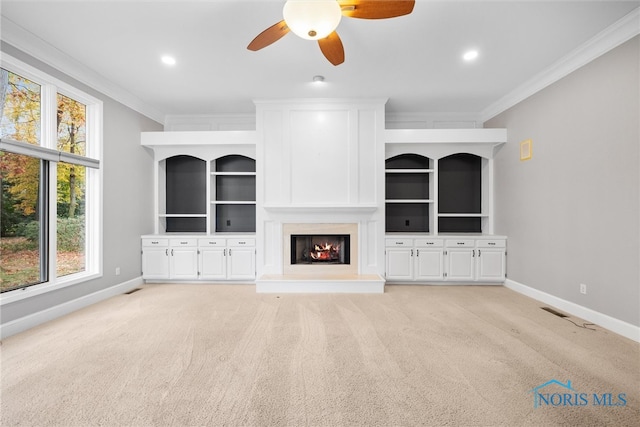 unfurnished living room with a wealth of natural light, light carpet, and ornamental molding