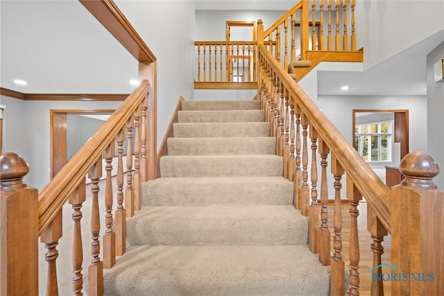 stairs with wood-type flooring and crown molding