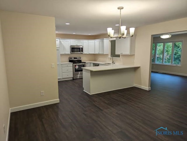 kitchen with kitchen peninsula, white cabinets, decorative light fixtures, appliances with stainless steel finishes, and dark hardwood / wood-style flooring