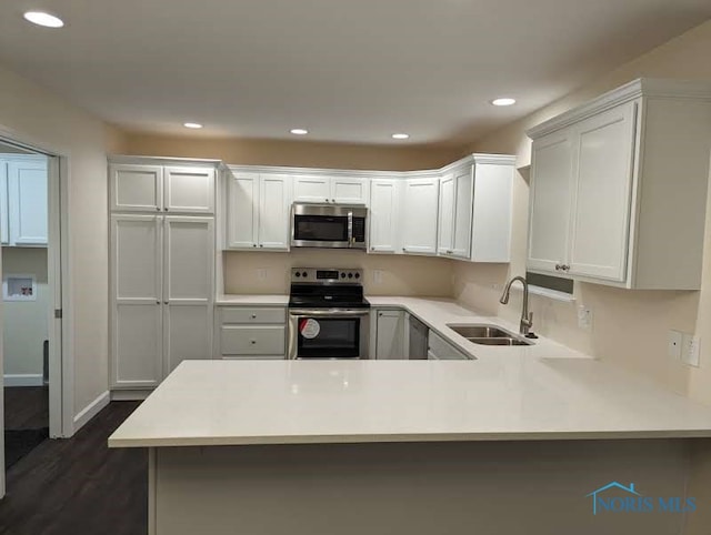 kitchen with appliances with stainless steel finishes, sink, kitchen peninsula, and white cabinets