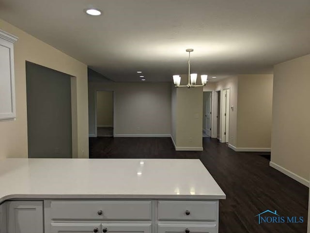 kitchen featuring kitchen peninsula, hanging light fixtures, an inviting chandelier, white cabinets, and dark hardwood / wood-style flooring