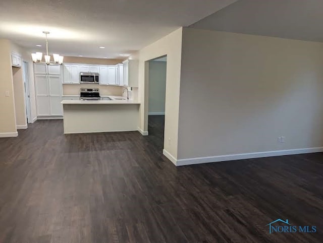 kitchen with white cabinets, stainless steel appliances, dark wood-type flooring, decorative light fixtures, and sink