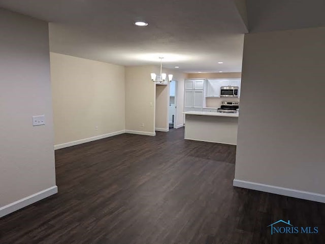 unfurnished living room with dark hardwood / wood-style floors and a chandelier