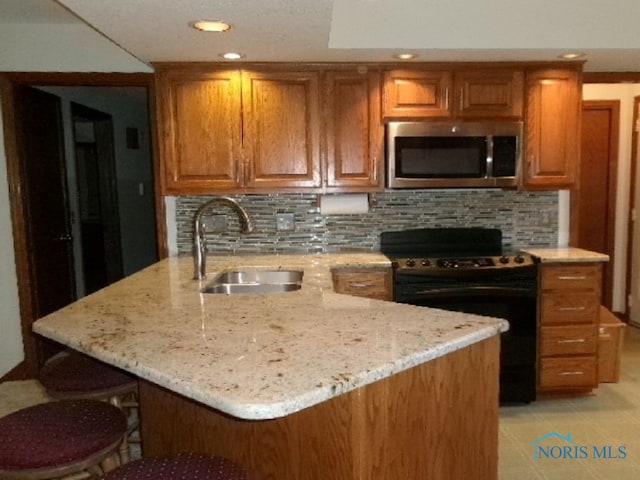 kitchen with tasteful backsplash, light stone countertops, sink, a kitchen breakfast bar, and black / electric stove