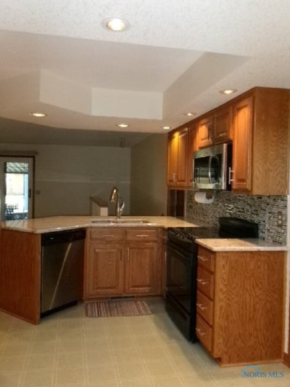 kitchen featuring kitchen peninsula, stainless steel appliances, sink, and backsplash