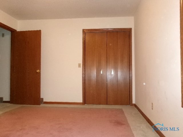 unfurnished bedroom with a closet and light colored carpet