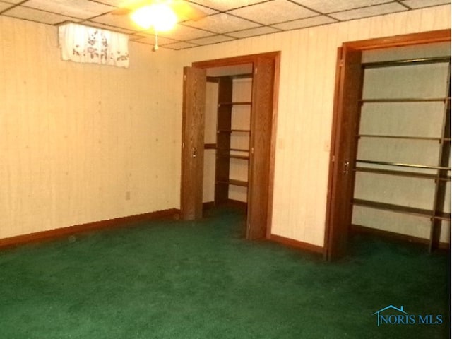 basement with a drop ceiling and dark carpet