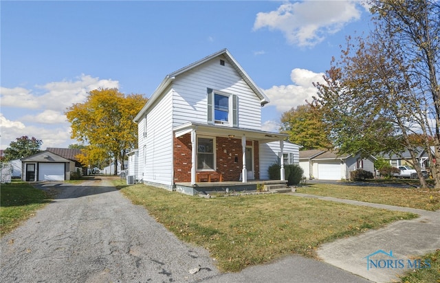 front facade with a front yard, an outdoor structure, a garage, and a porch