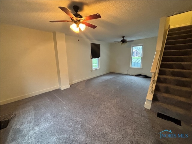 carpeted empty room with ceiling fan and a textured ceiling