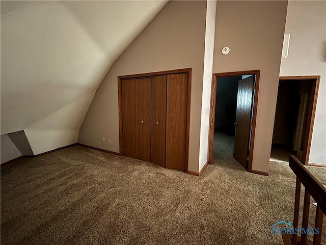 unfurnished bedroom with a closet, high vaulted ceiling, and carpet flooring