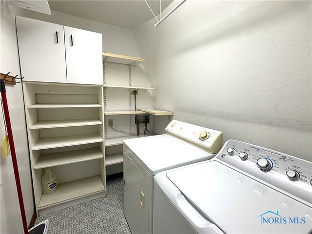 clothes washing area featuring cabinets and separate washer and dryer