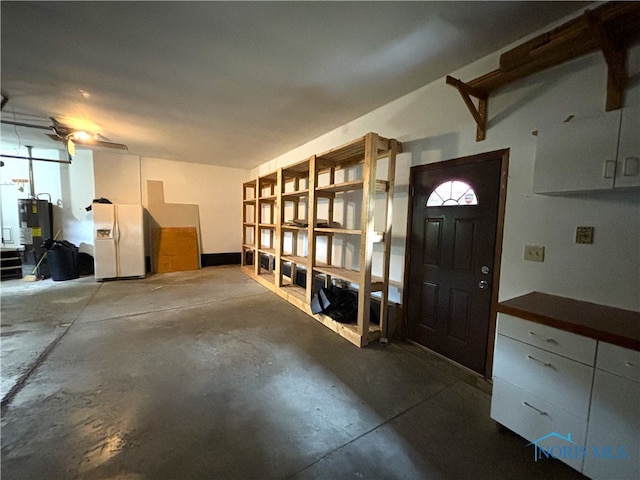 garage featuring water heater and white refrigerator with ice dispenser