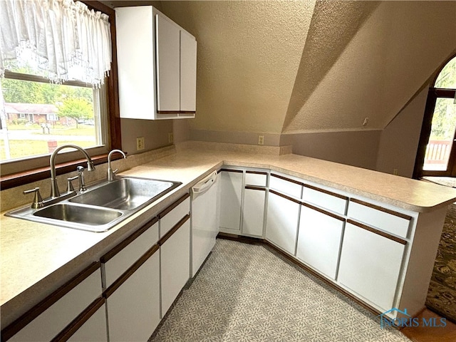 kitchen with kitchen peninsula, white dishwasher, sink, white cabinetry, and a textured ceiling