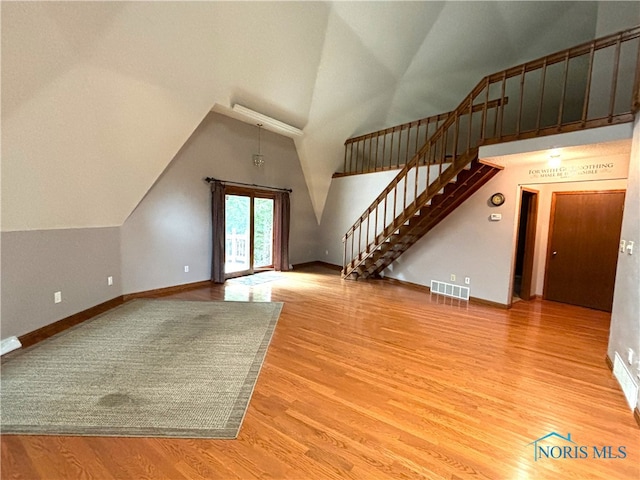 unfurnished living room featuring high vaulted ceiling and hardwood / wood-style floors