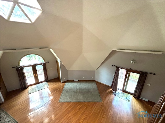 additional living space featuring lofted ceiling, hardwood / wood-style floors, and french doors