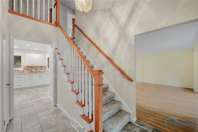 staircase with a high ceiling and wood-type flooring