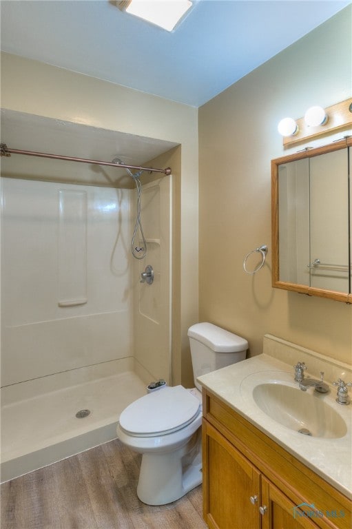 bathroom featuring vanity, a shower, hardwood / wood-style flooring, and toilet