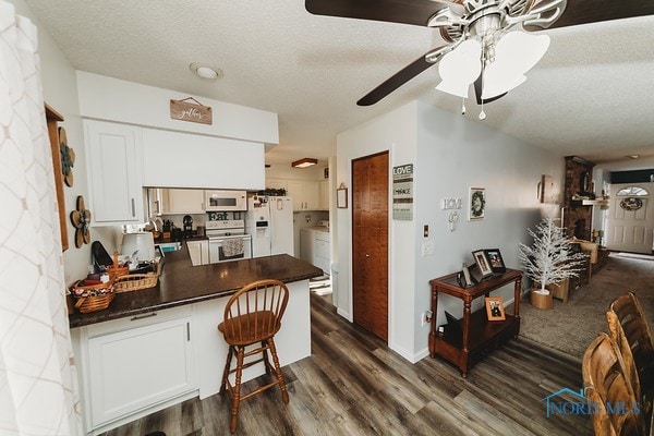 kitchen with ceiling fan, a textured ceiling, white cabinetry, dark hardwood / wood-style floors, and white appliances