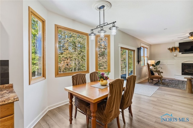 dining room with light hardwood / wood-style floors, a fireplace, and ceiling fan