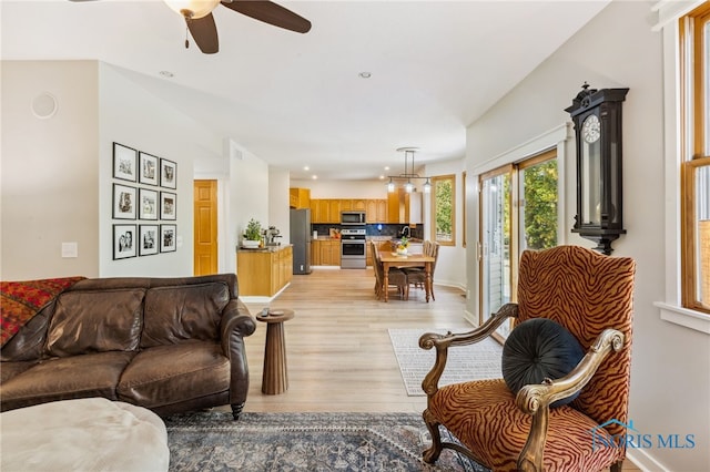 living room with sink, light wood-type flooring, and ceiling fan