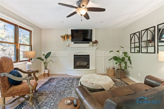 living room featuring a fireplace, light hardwood / wood-style floors, and ceiling fan