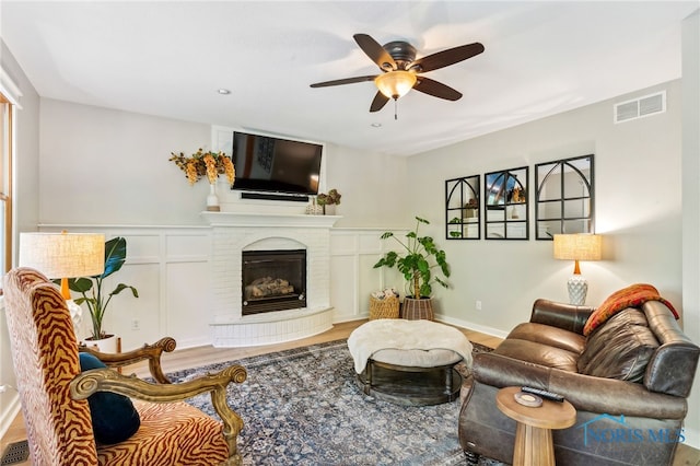 living room featuring ceiling fan, hardwood / wood-style flooring, and a fireplace