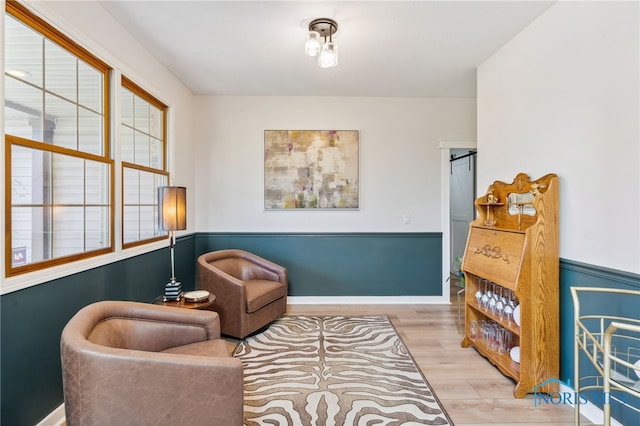 sitting room featuring a barn door and light wood-type flooring