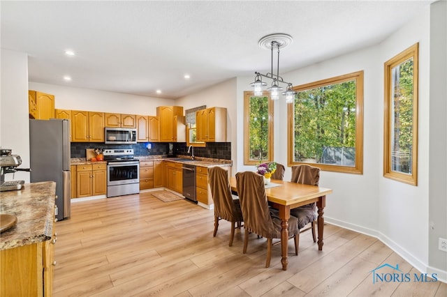 kitchen featuring backsplash, sink, pendant lighting, light hardwood / wood-style floors, and stainless steel appliances