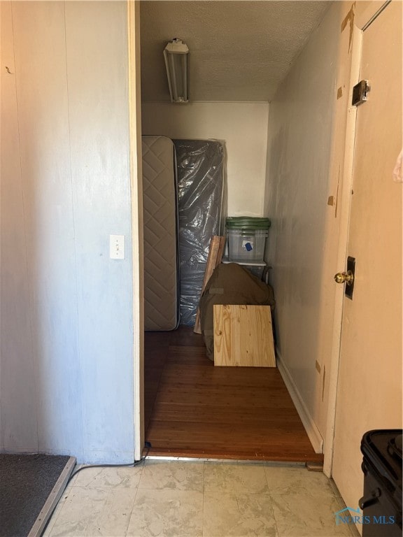 hallway with a textured ceiling and light hardwood / wood-style flooring