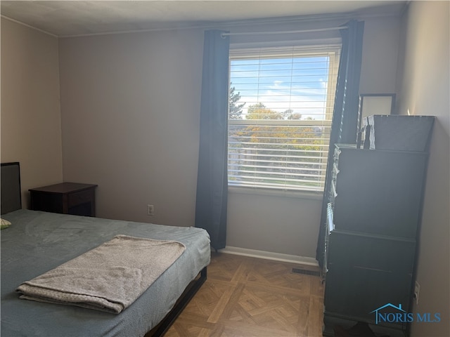 bedroom featuring ornamental molding, multiple windows, and parquet floors