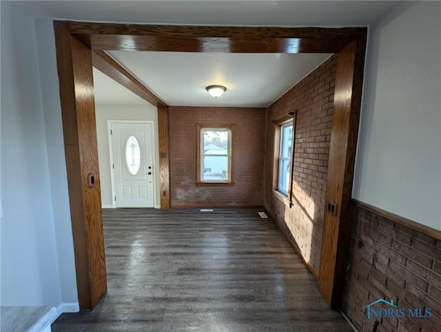 entryway featuring dark wood-type flooring and brick wall