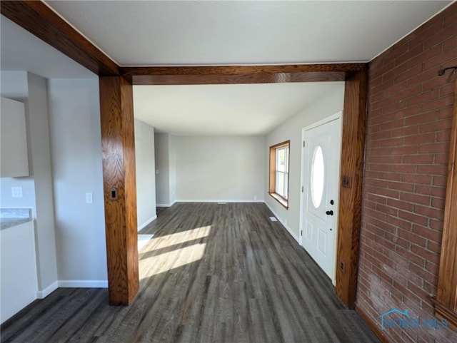 foyer entrance with brick wall and dark hardwood / wood-style flooring